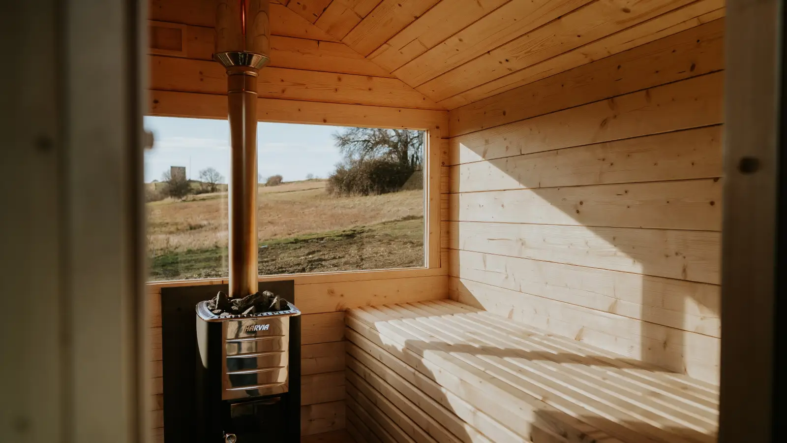 Świerkowe ławki oraz piec na drewno w saunie ogrodowej Stodoła